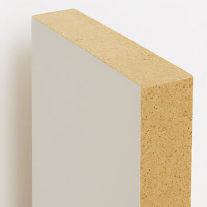 A close-up view of a rectangular piece of particle board with a smooth, light-colored laminate surface and exposed, textured wood particle edges.