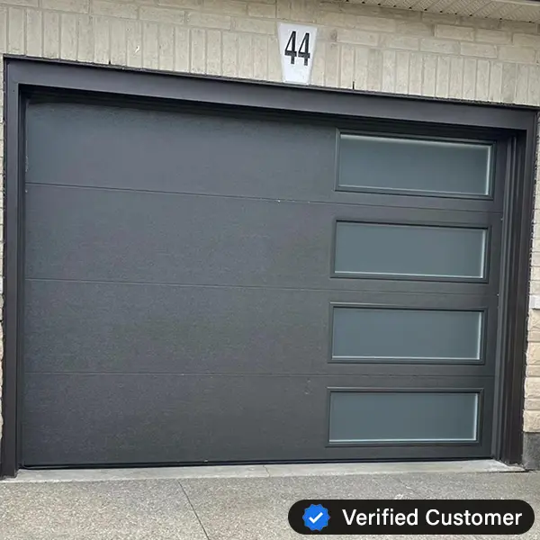 verified-garage-door-repair-GTA A modern black garage door with four horizontal rectangular windows on the right side, set in a light brick exterior below house number 44. A Verified Customer badge is shown in the corner, highlighting trusted Garage Door Repair services.