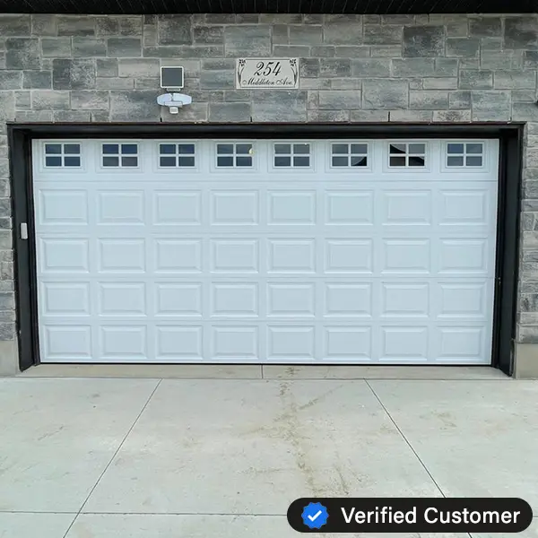 verified-garage-door-repair-toronto A white garage door with small windows along the top row is set in a gray brick exterior, showcasing expert Garage Door Repair. Above the door, a house number sign reads 254, and a Verified Customer badge is visible in the corner.